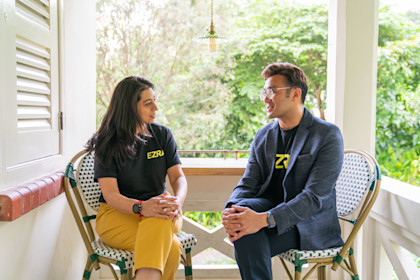 Two colleagues sat outside on chairs talking about leadership development.