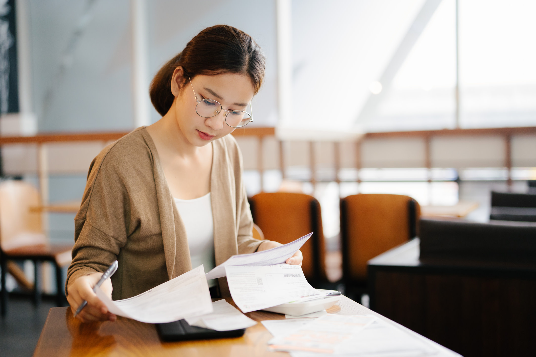 Asian woman looking through paperwork. 