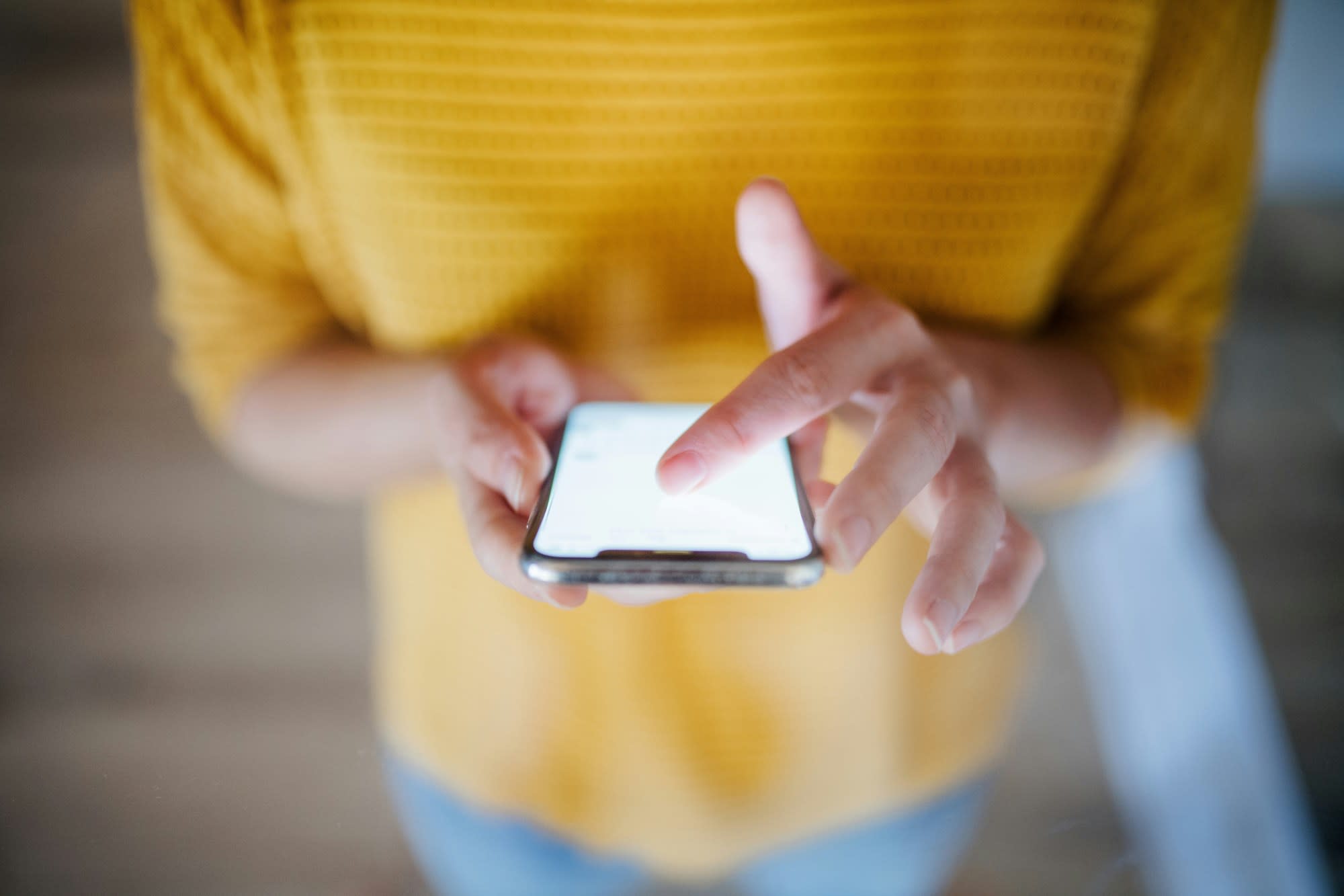 Woman in yellow top scrolling on her smartphone.