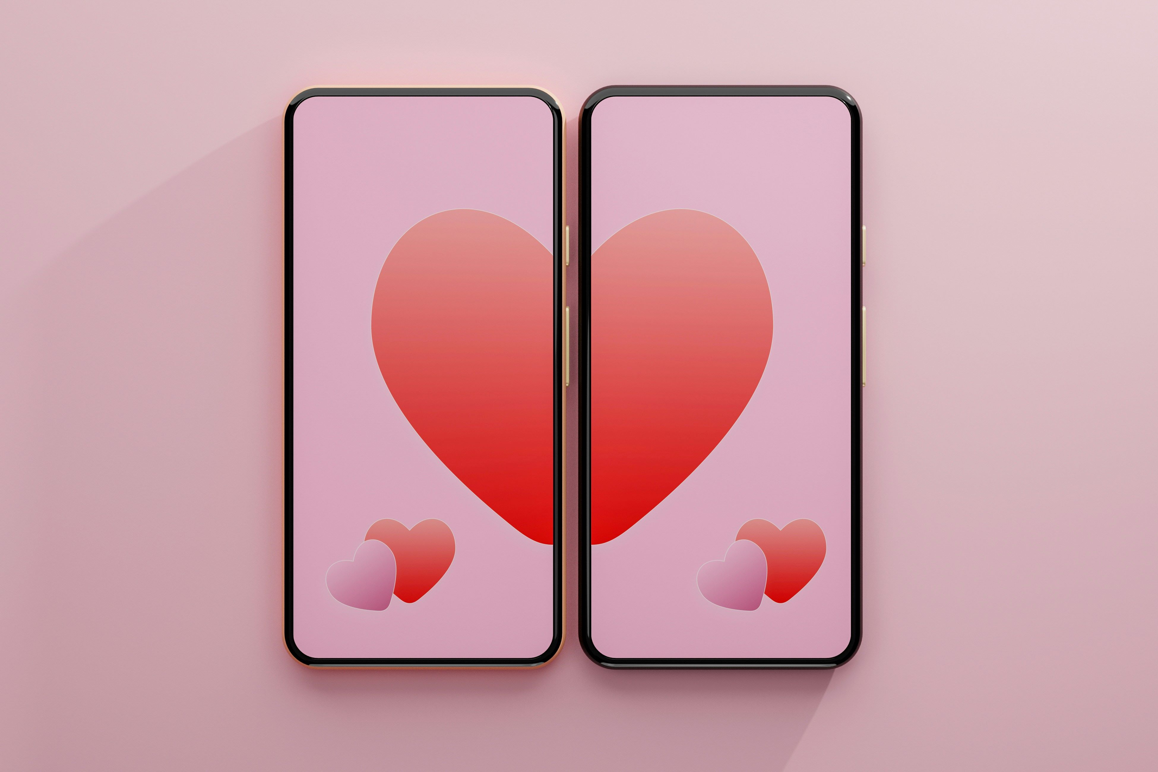 Two smartphones with half a heart on each screen are pushed together to make a whole heart.