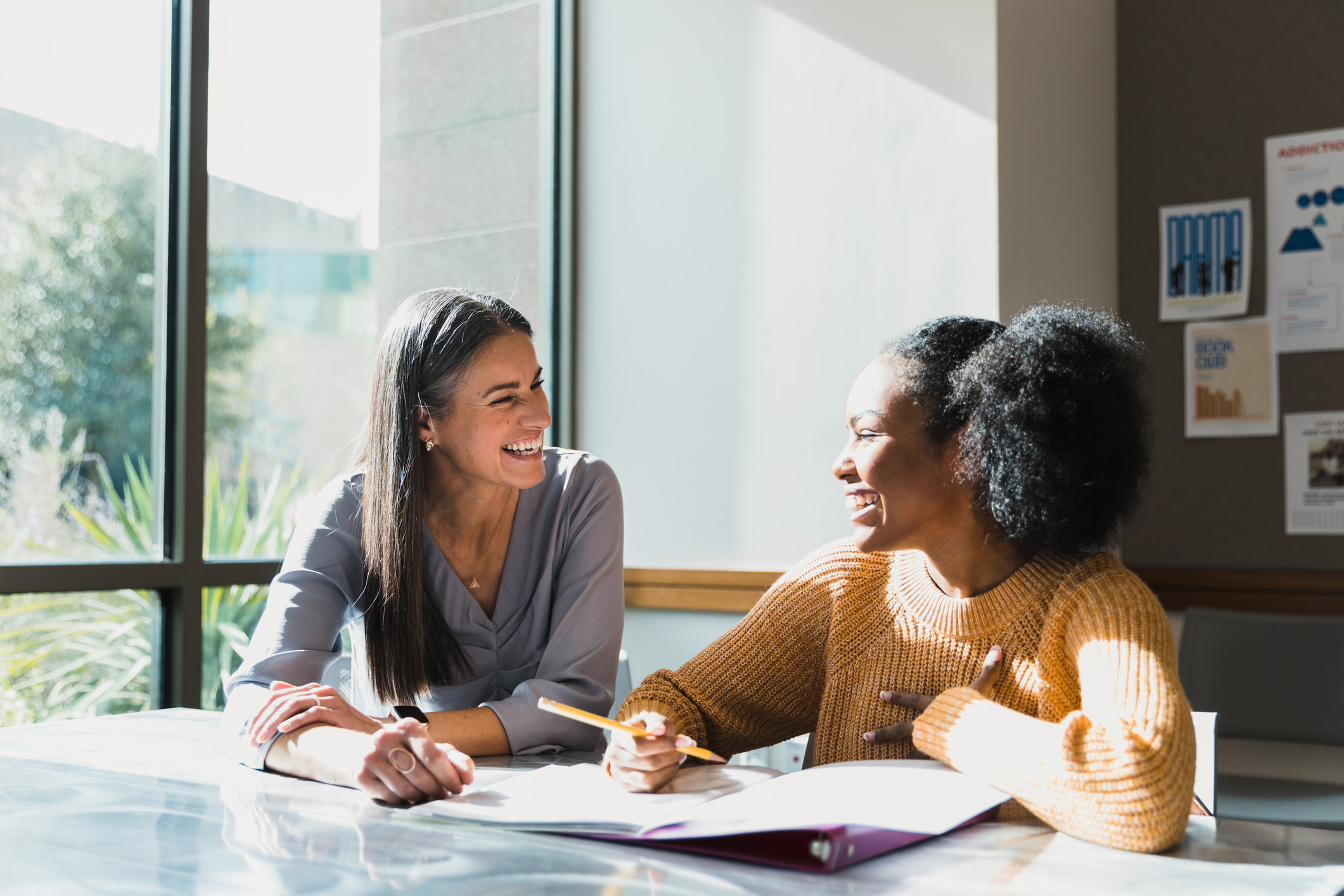Two women sat at a table, working together on some documents.