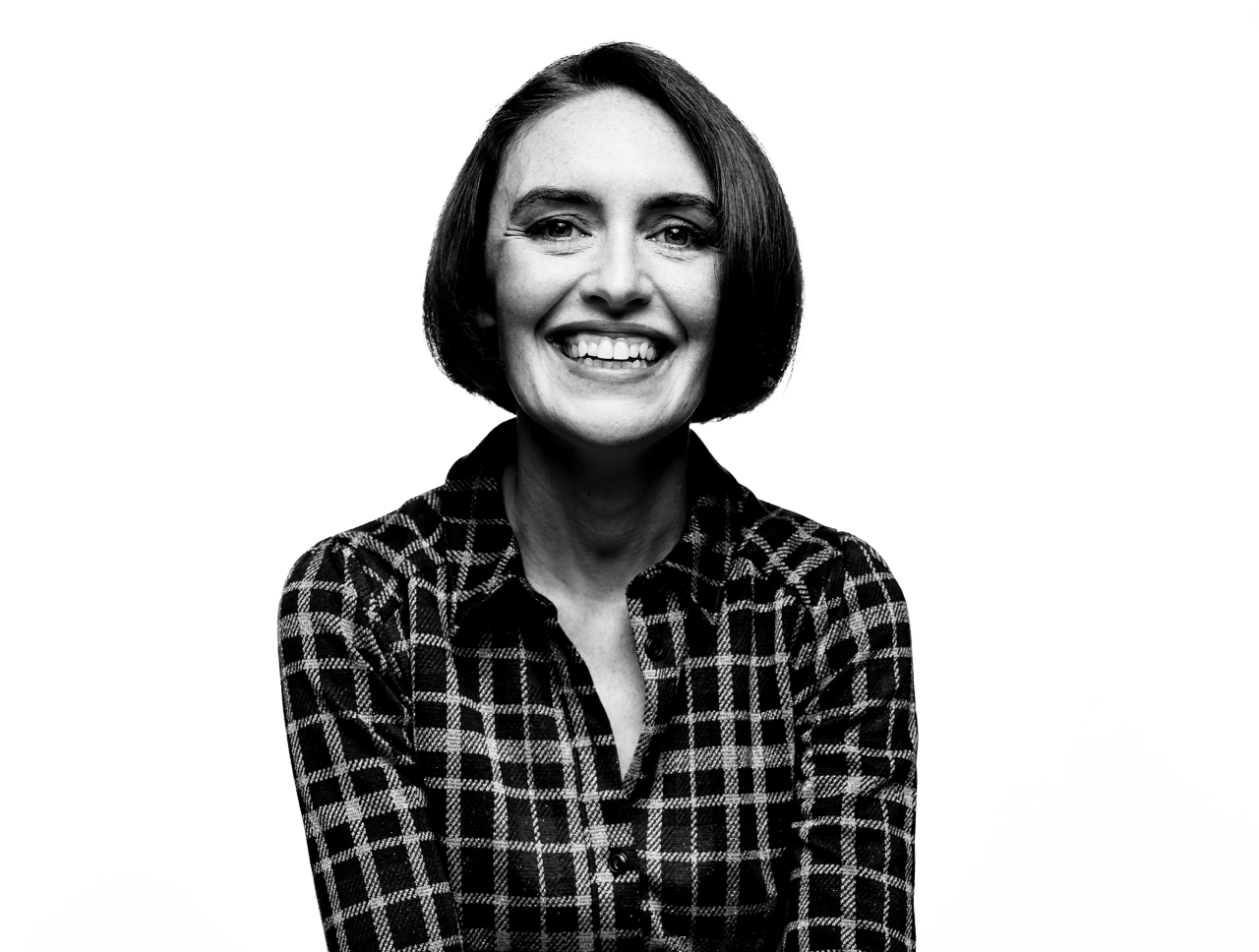 Woman wearing a checked shirt, smiling at the camera.