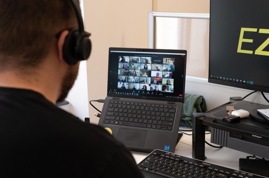 A man wearing headphones, facing a screen on a virtual call with new joiners who are being virtually onboarded. 