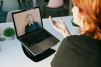 Woman sat at her desk with her laptop, speaking to a colleague remotely via Zoom call.