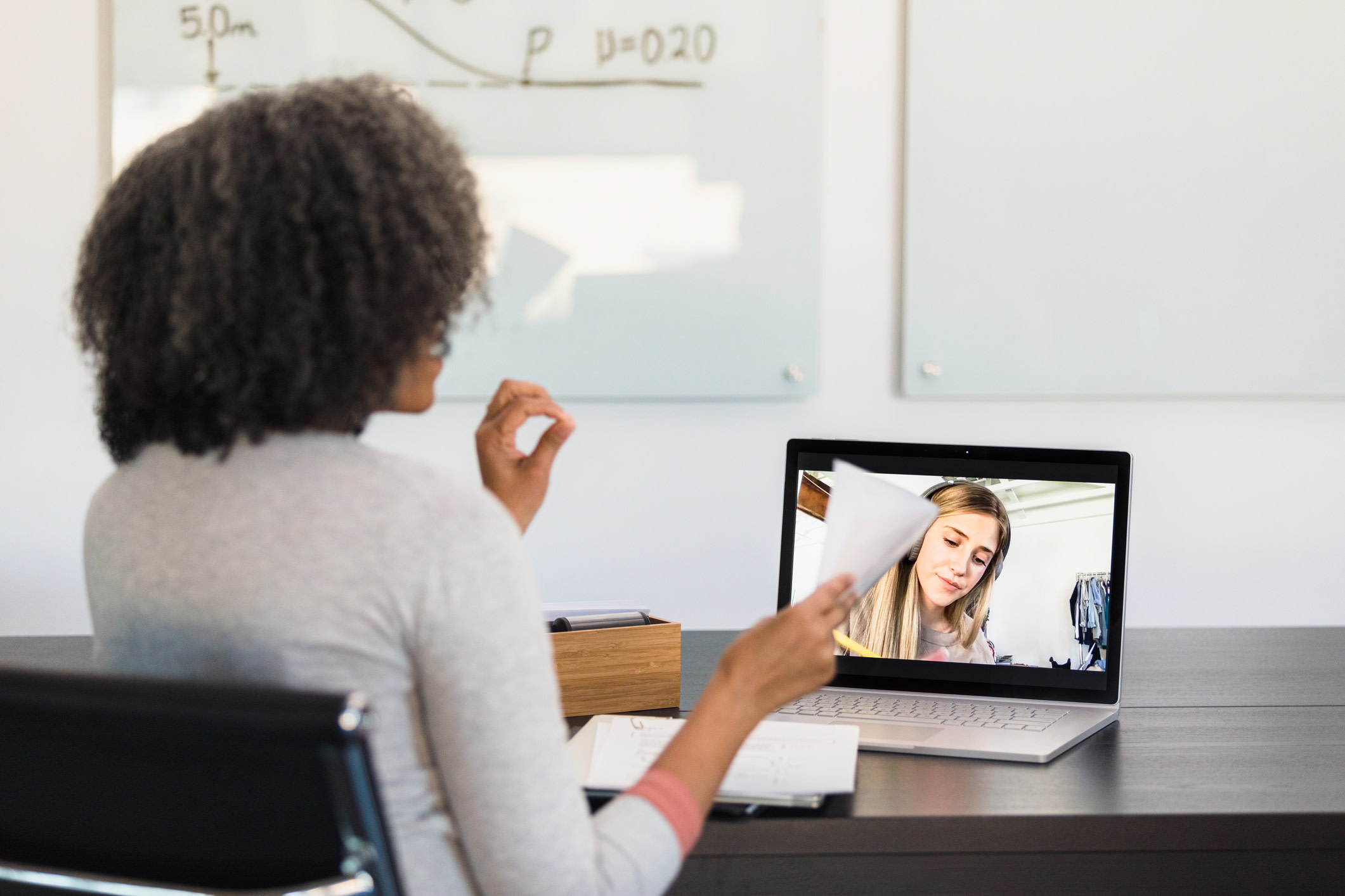 A woman with her back facing the camera having a video call.