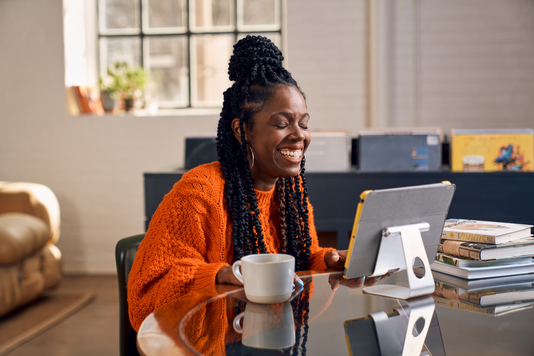 Smiling woman in orange knitted jumper, using the EZRA coaching app on a tablet
