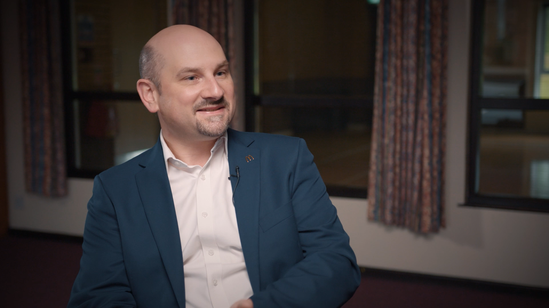 Alex Snelling, Director de Talento en McDonald’s, lleva una chaqueta azul oscuro con una camisa blanca.