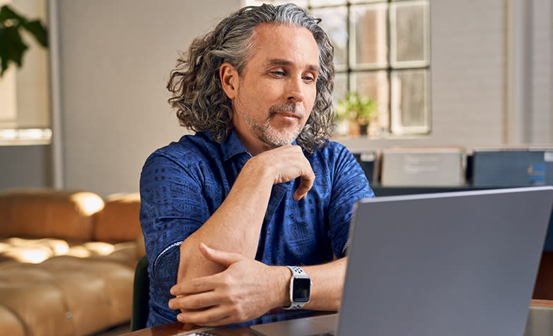 A middle-aged man smiling looking at his laptop.