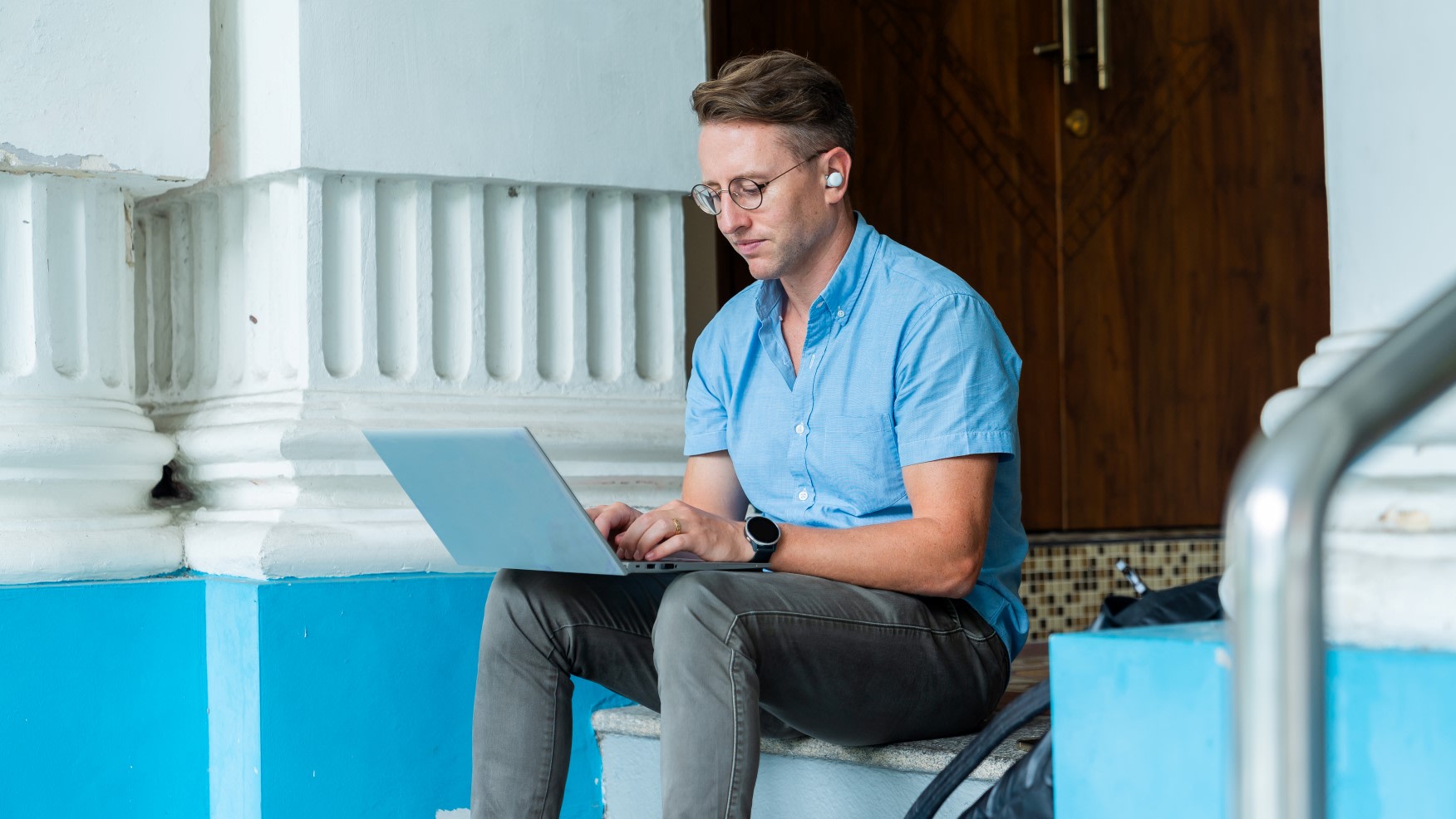 A man sitting on some steps with a laptop