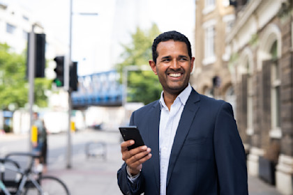 Man in a blue suit using is phone on the street.