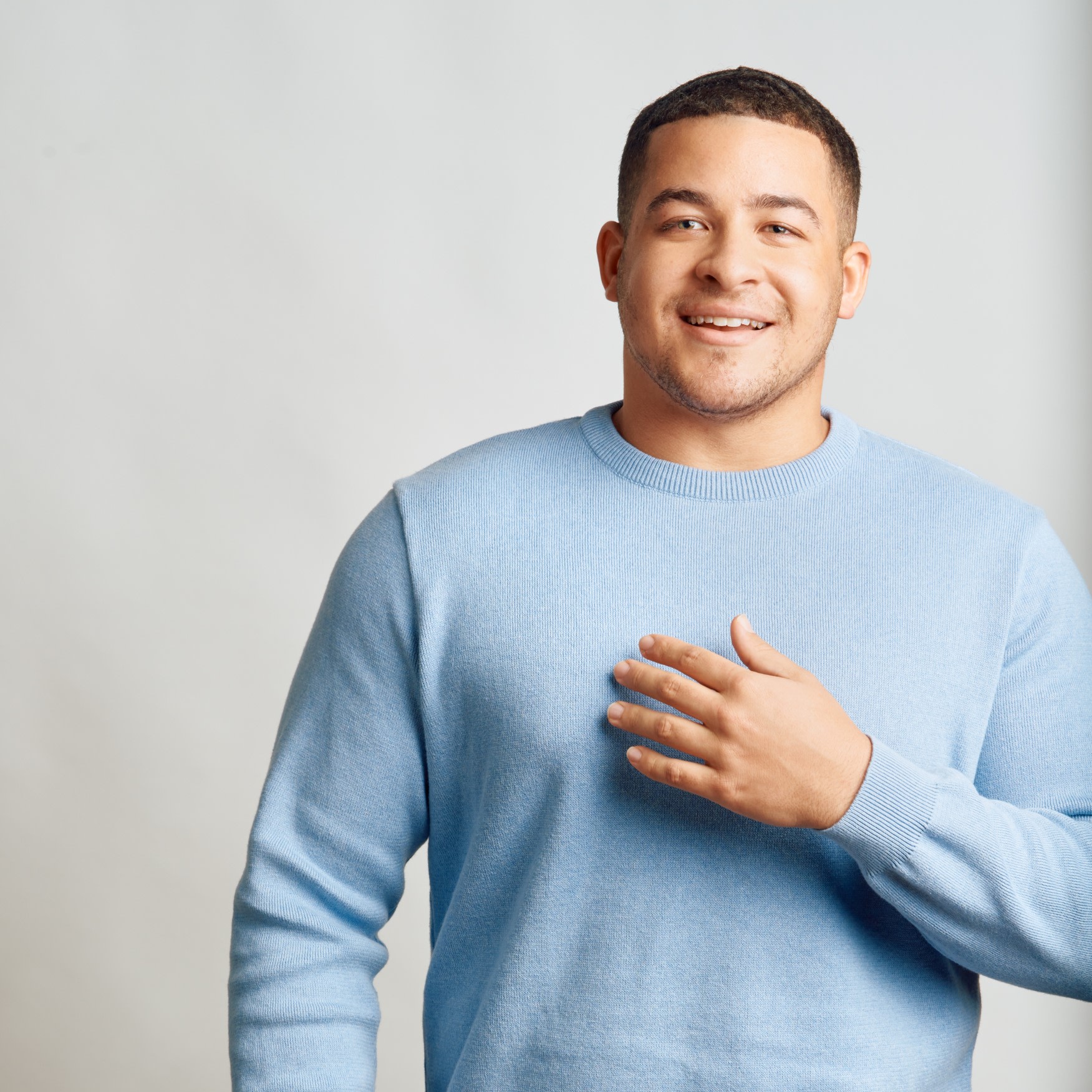 Man smiling and looking into camera with his hand on his chest