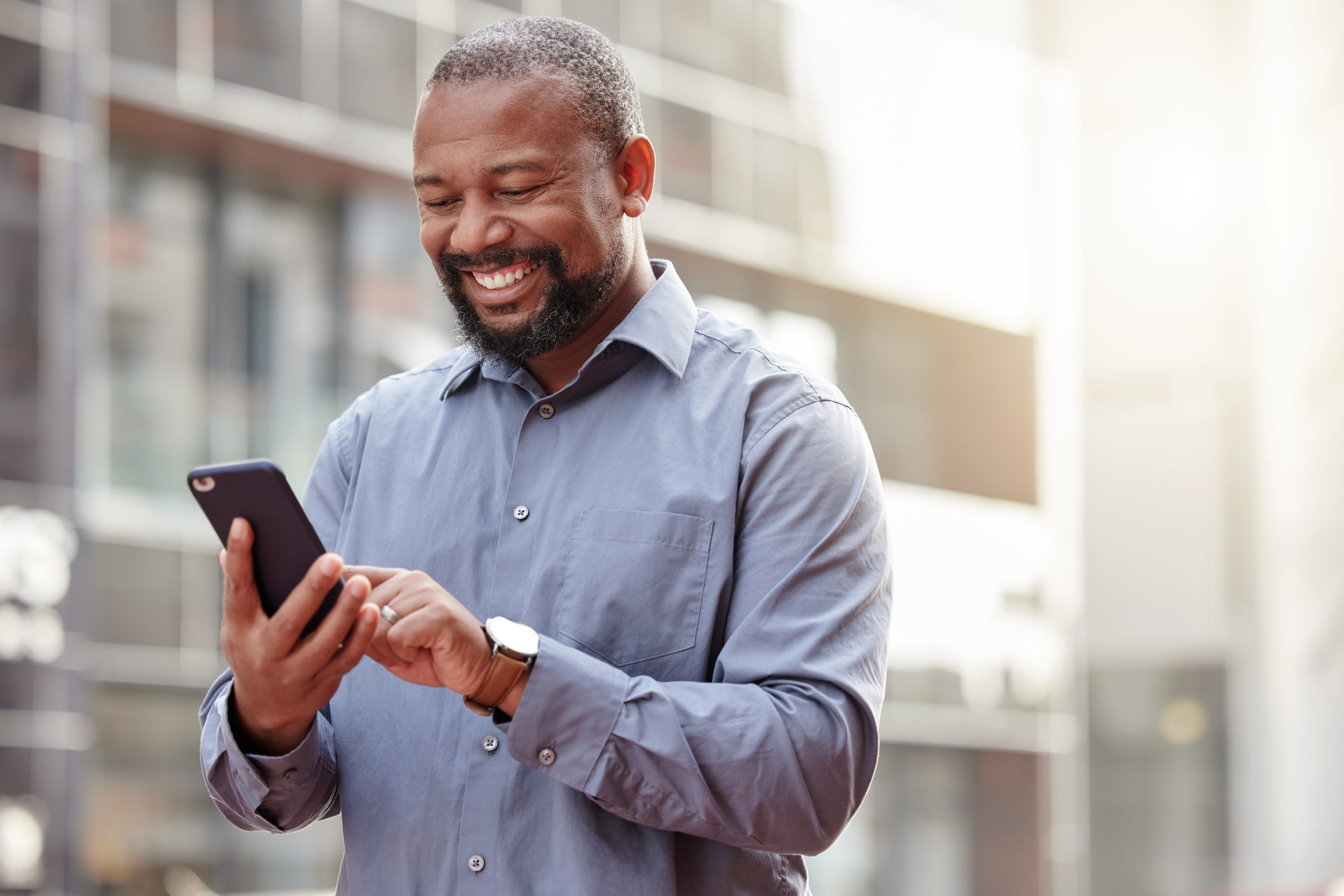 A man smiling and looking at his phone.