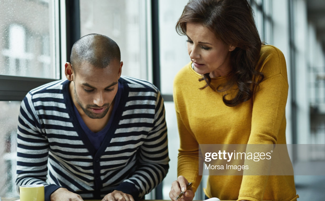 Donna con maglione giallo e uomo con cardigan a righe che lavorano insieme