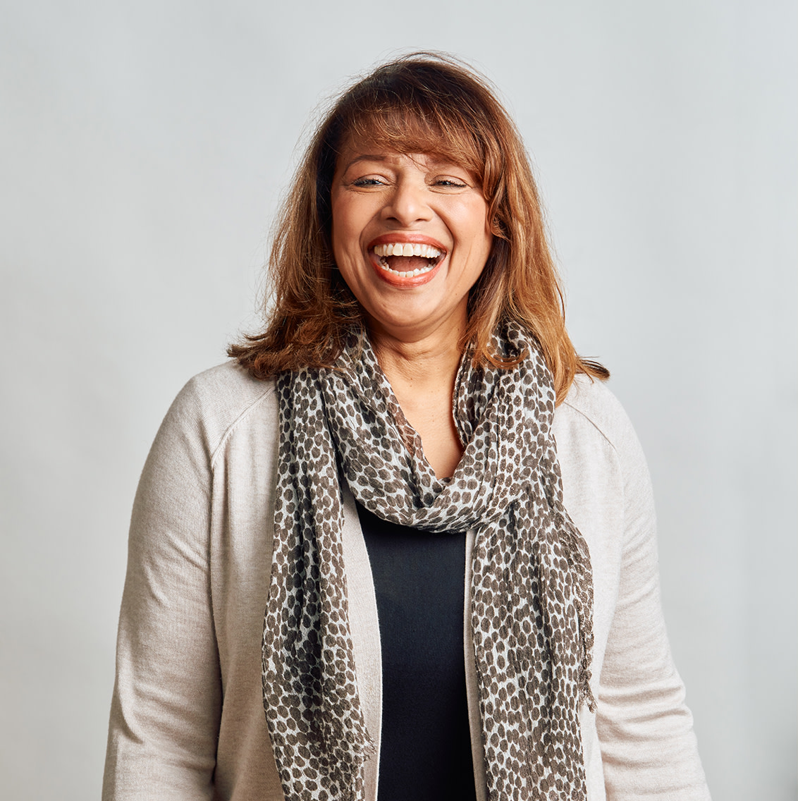 Laughing lady wearing grey cardigan and spotted neckscarf