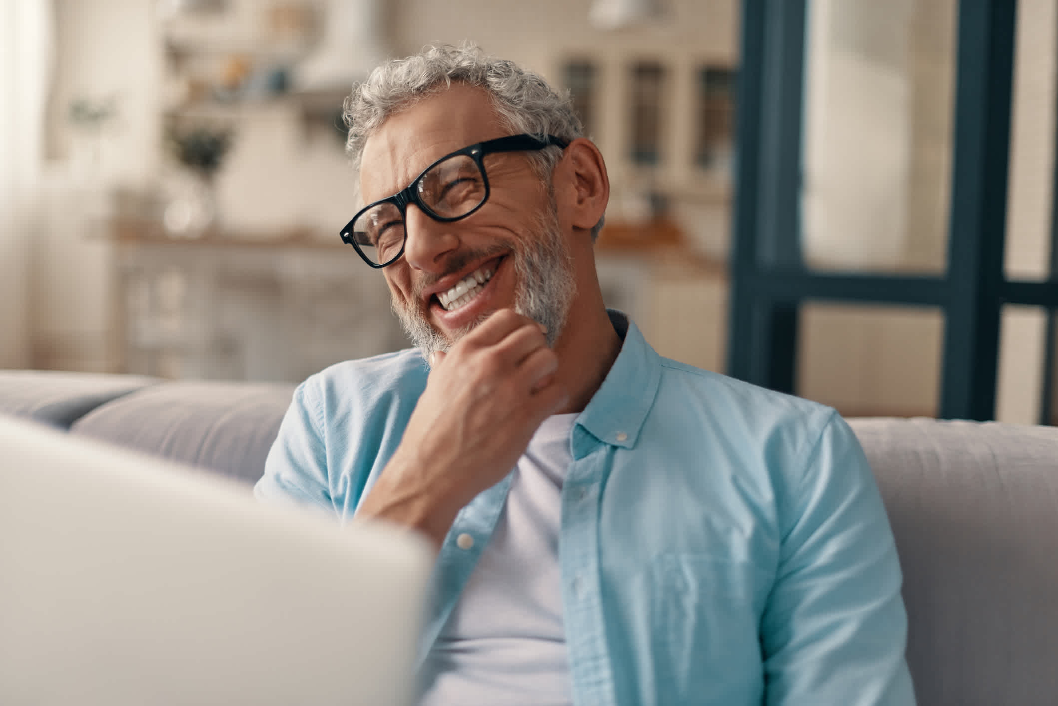 Middle aged man laughing in front of a computer.
