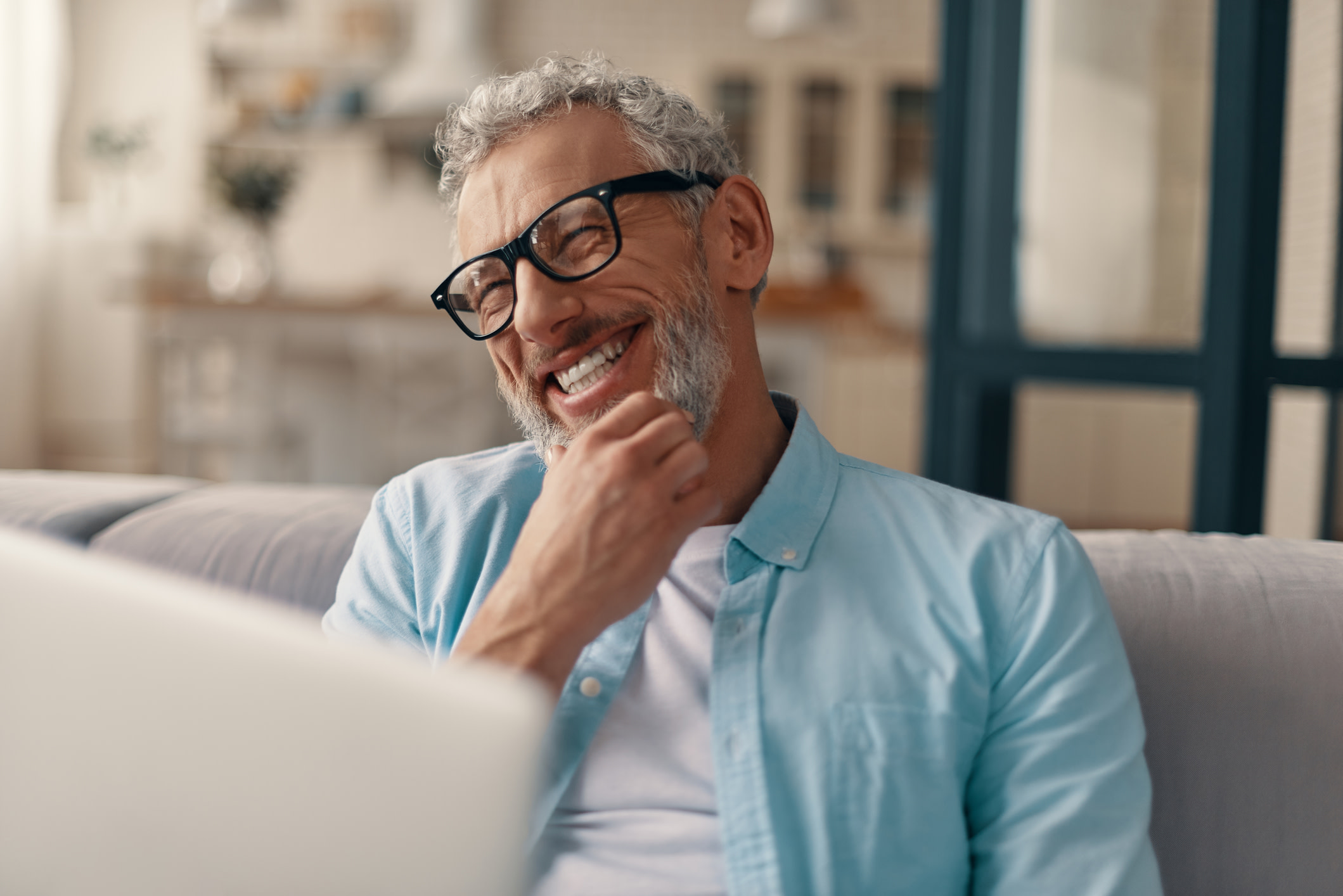 Middle aged man laughing in front of a computer.