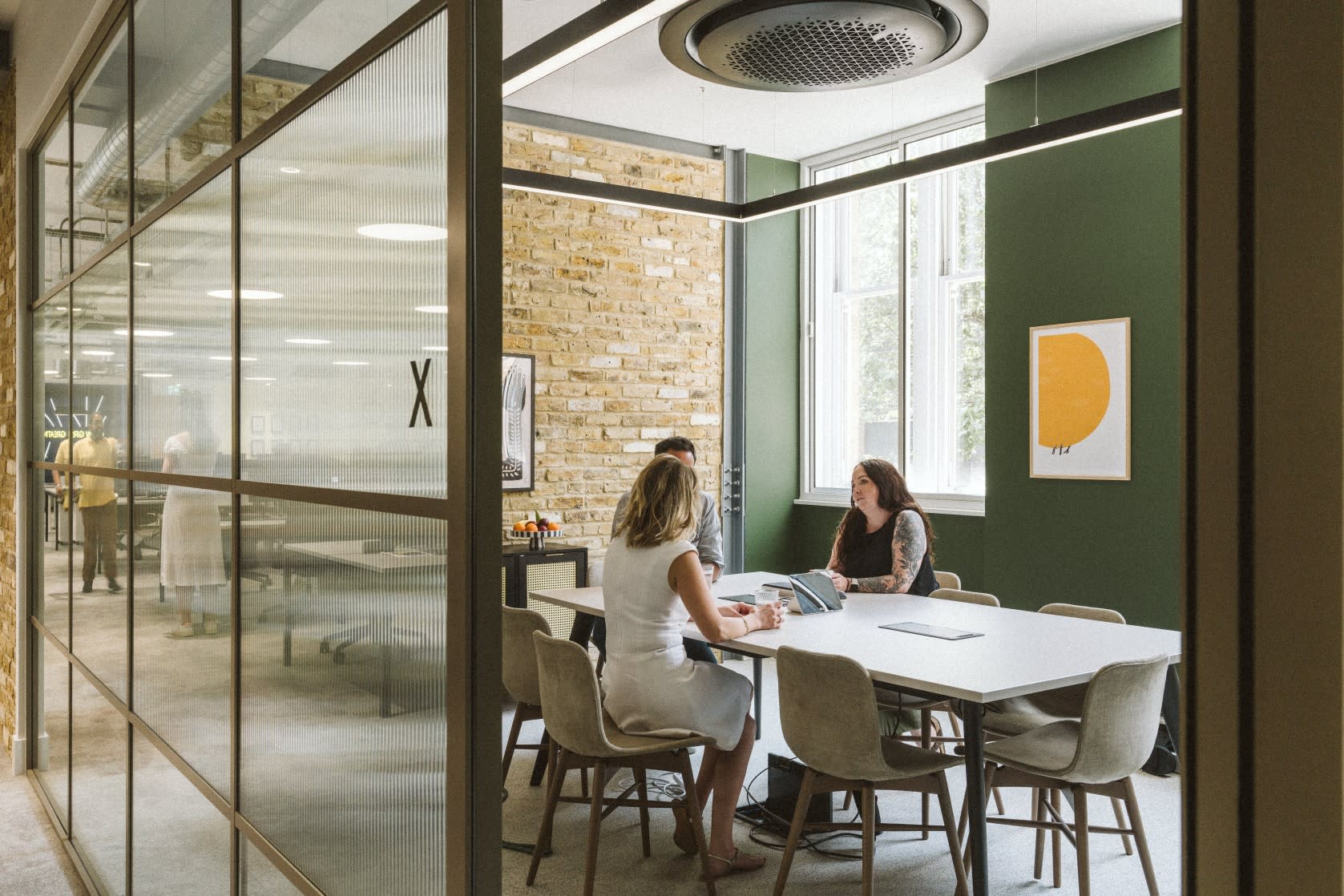 Three people sat in a meeting room at a large desk, going through the exit process for employees.