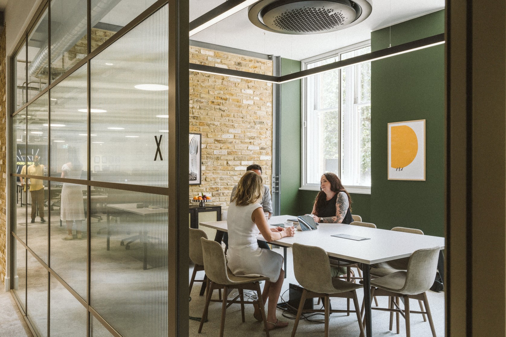 Three people sat in a meeting room at a large desk, going through the exit process for employees.