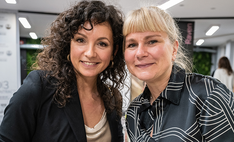 Two female executive coaches with heads together, one with dark hair, one with blonde