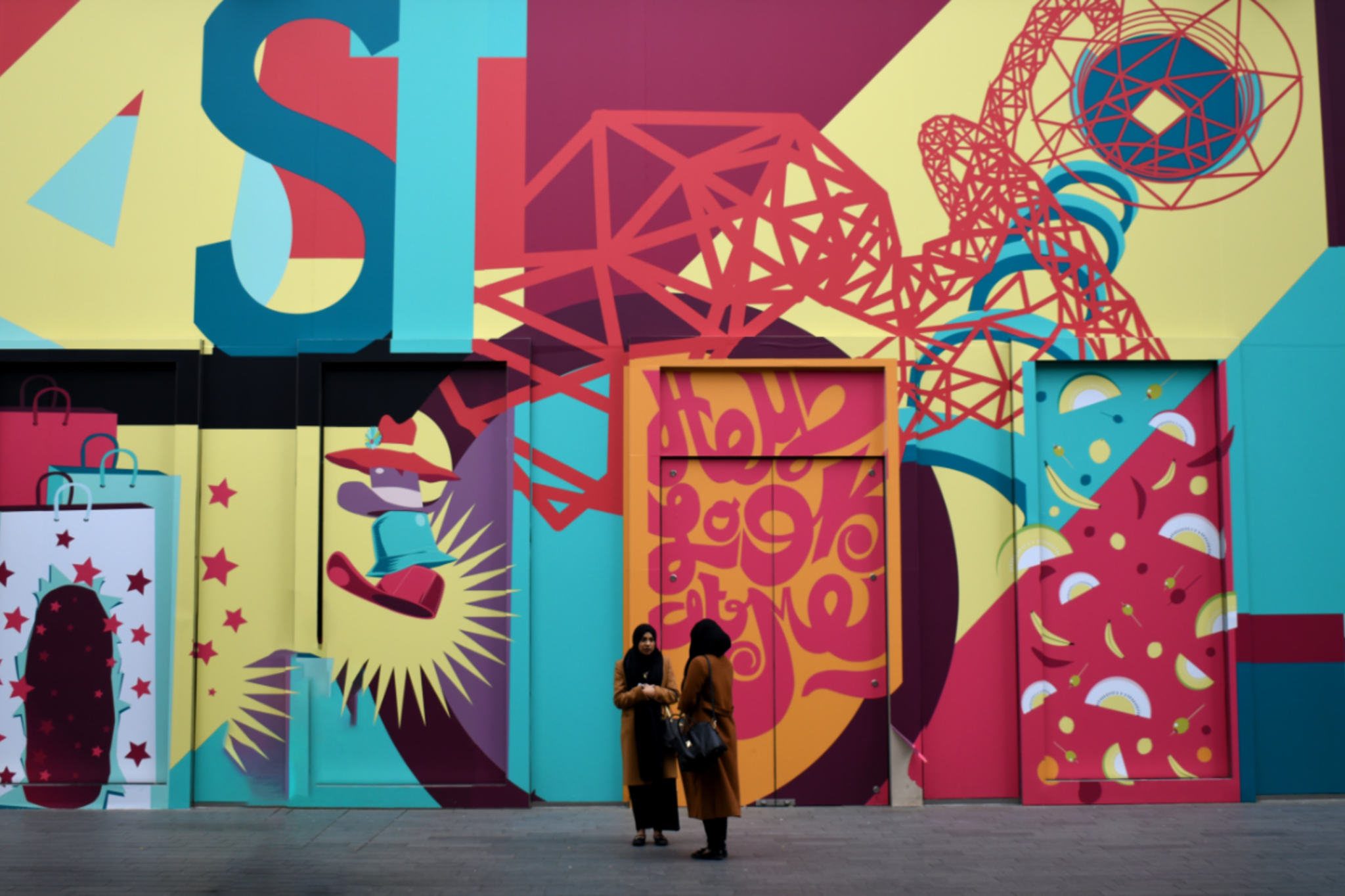 Two women stand outside a colorfully painted building