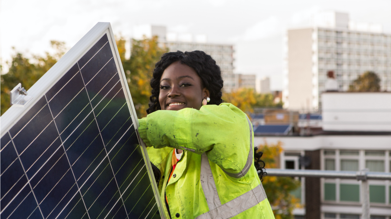 Woman in hi-viz jacket, installing a solar panel