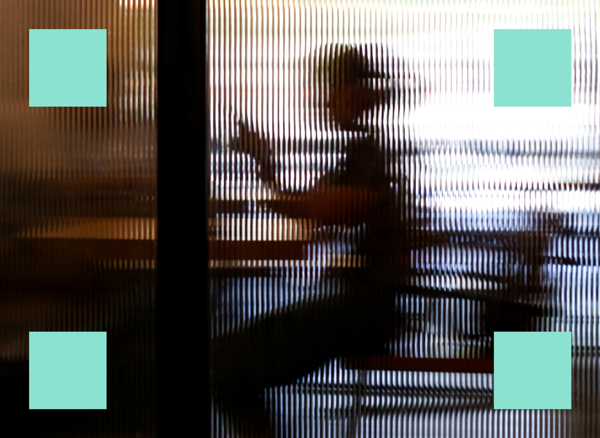 Person using smartphone, distorted by corrugated glass divider