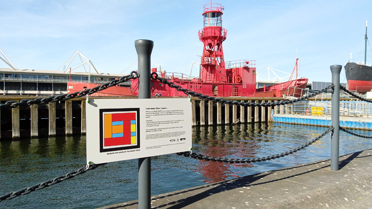 An AR marker (image and text on a pole) in-front of a red ship