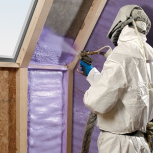 Worker in protective clothing spraying wall insulation. 