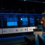 image of woman with laptop sat in front of computer servers