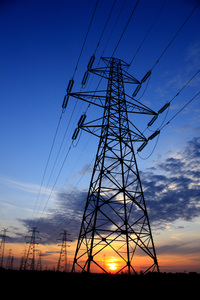 An electricity pylon with the sun setting in the back.