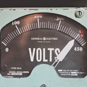 Image of vintage electricity voltage meter with white dial. 