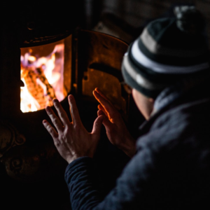 Man warming his hands in front of a small fire. 
