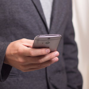 Image of a man in grey suit holding mobile phone.
