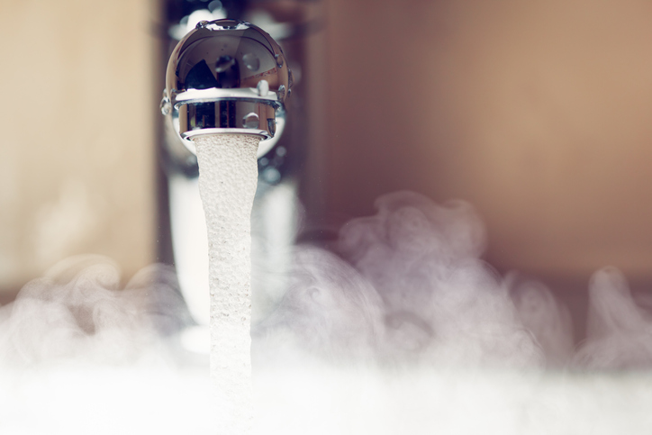 close up view of a silver water tap with hot water and steam