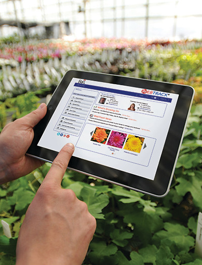 Finger on tablet of WebTrack screen in greenhouse
