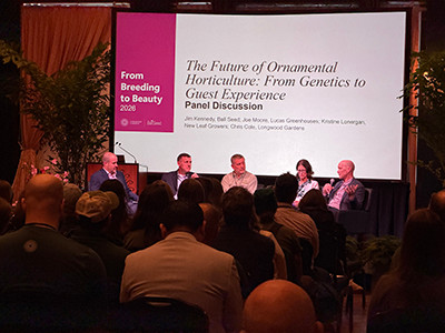 A panel discussion in front of a large screen on stage.