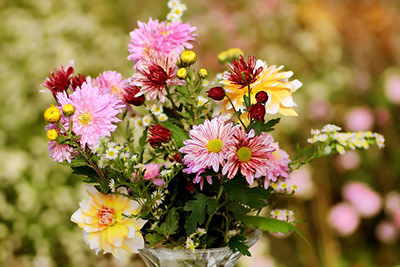 A vase of flowers in pink, yellow and red.