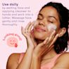 A young black woman, her eyes closed, using foaming cleanser on her face next to 'looking good' icon