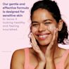 Young black woman using foaming cleanser on her face and smiling
