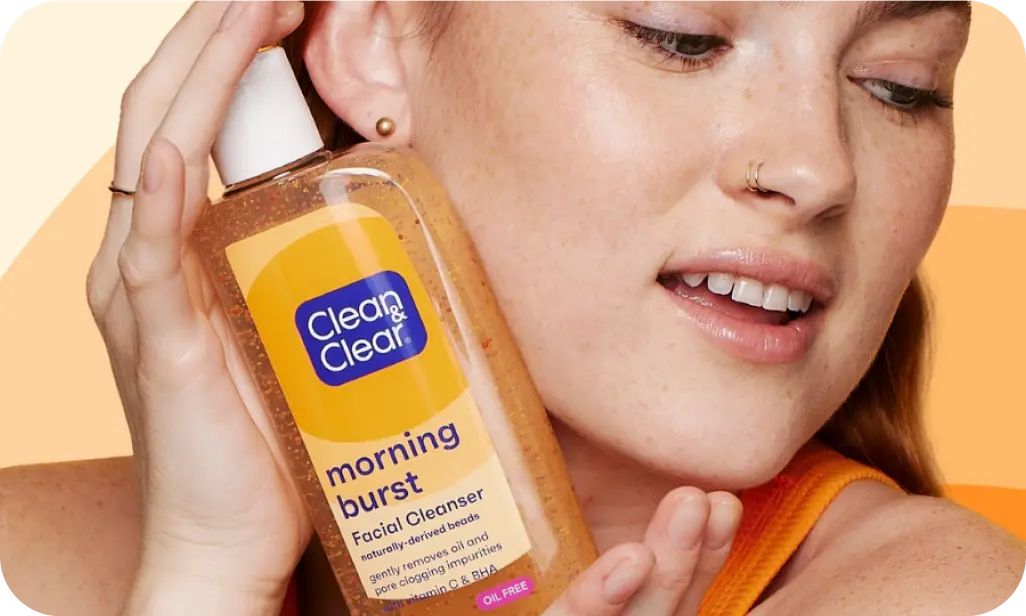 Clean & Clear skincare products featuring Vitamin C enriched Morning Burst Facial Cleanser held by a smiling woman.