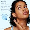 Young woman applying acne gel on her pimples on her face