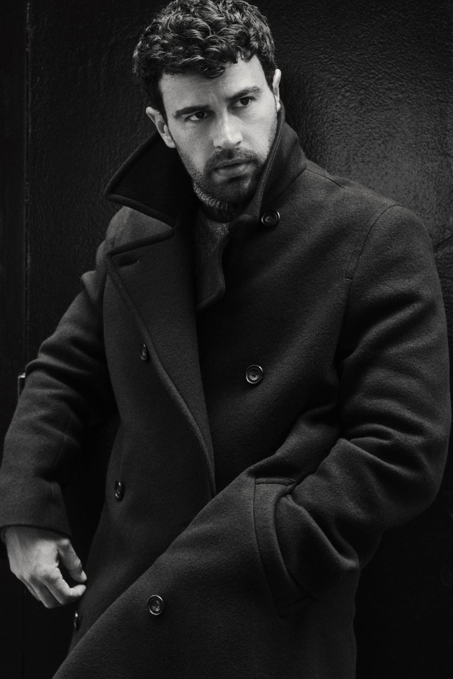 Actor Theo James styled in a Gant peacoat layered over a Gant knit sweater in a close-up black & white portrait.