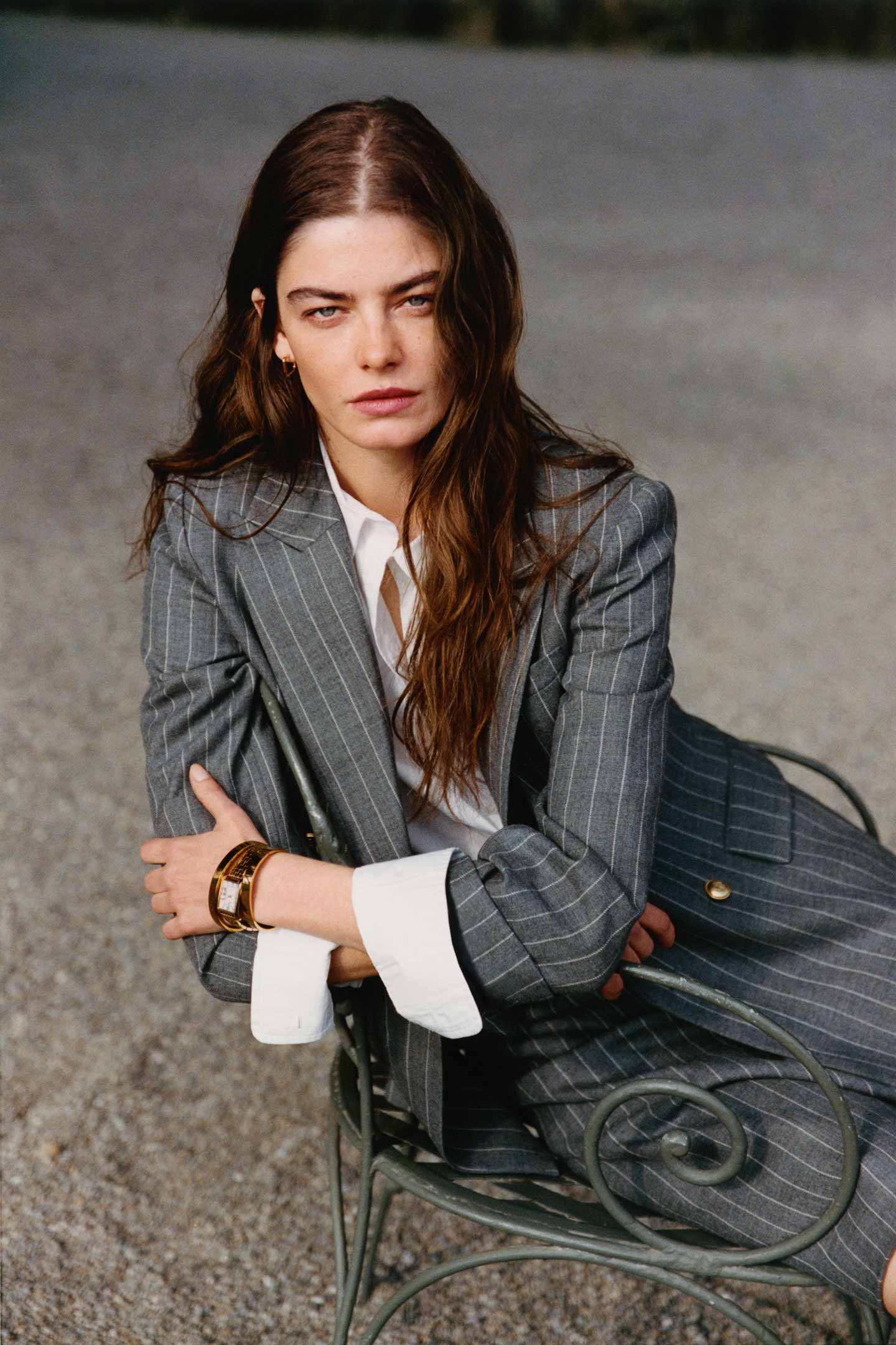 Model styled in a GANT grey pinstripe suit and white shirt seated outdoors.