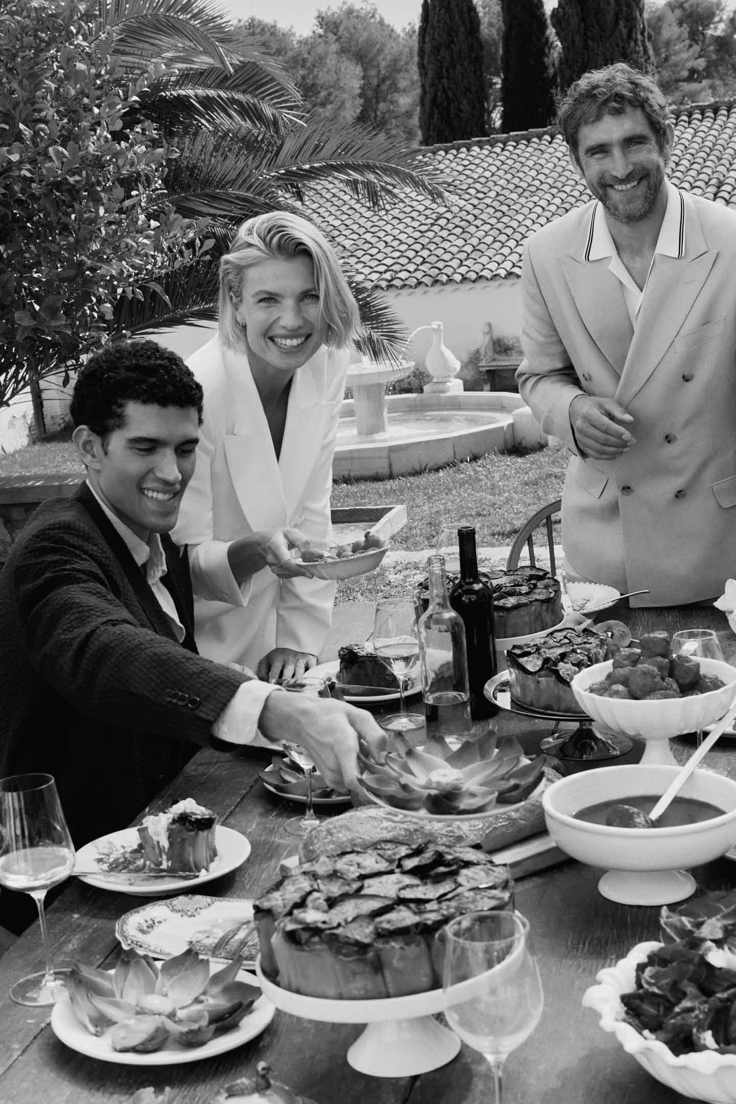 People in Gant outfits gather around an outdoor table with food during a meal.