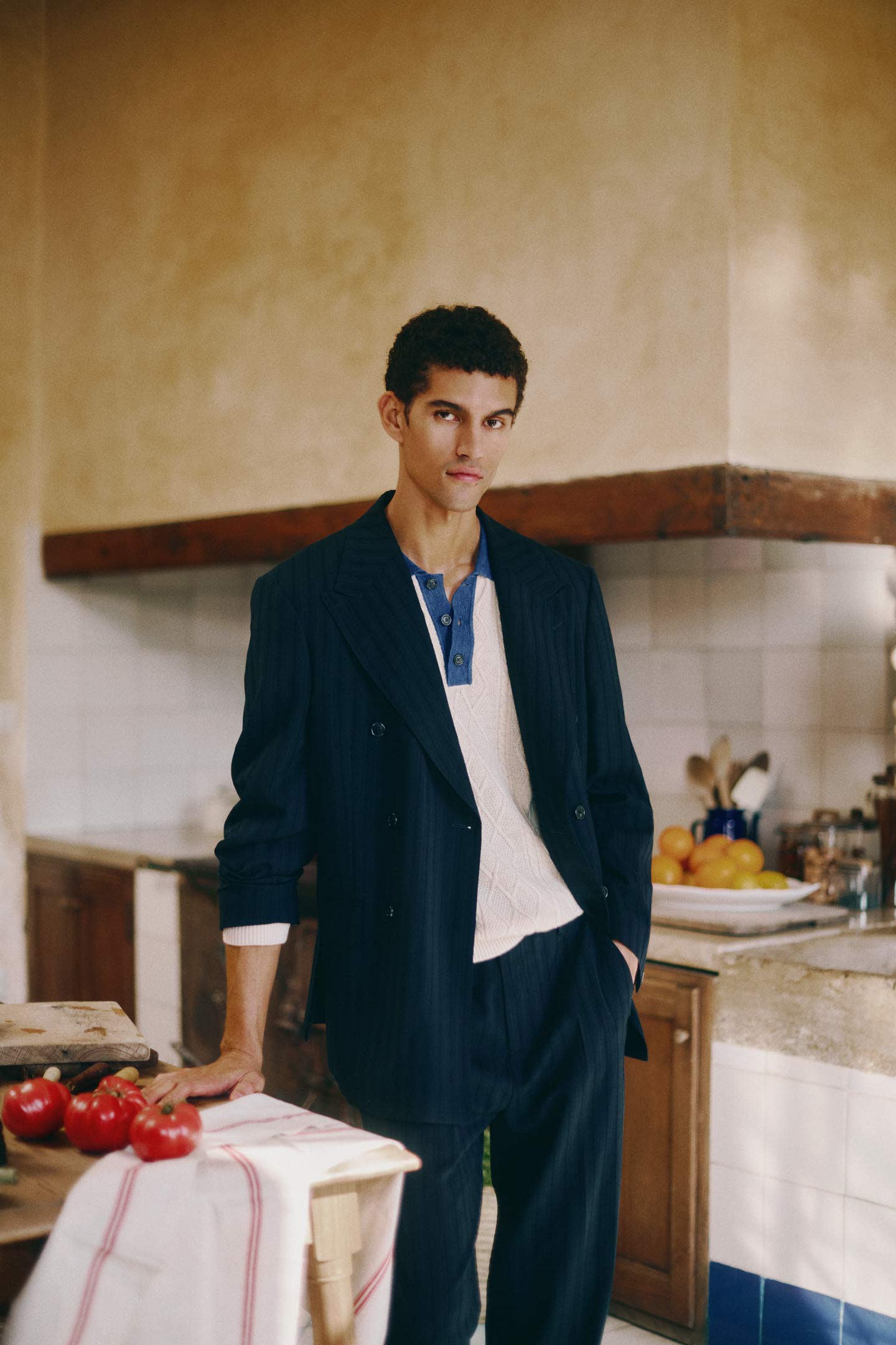 Man wearing a Gant navy double‑breasted blazer over a textured henley shirt while standing in a kitchen setting