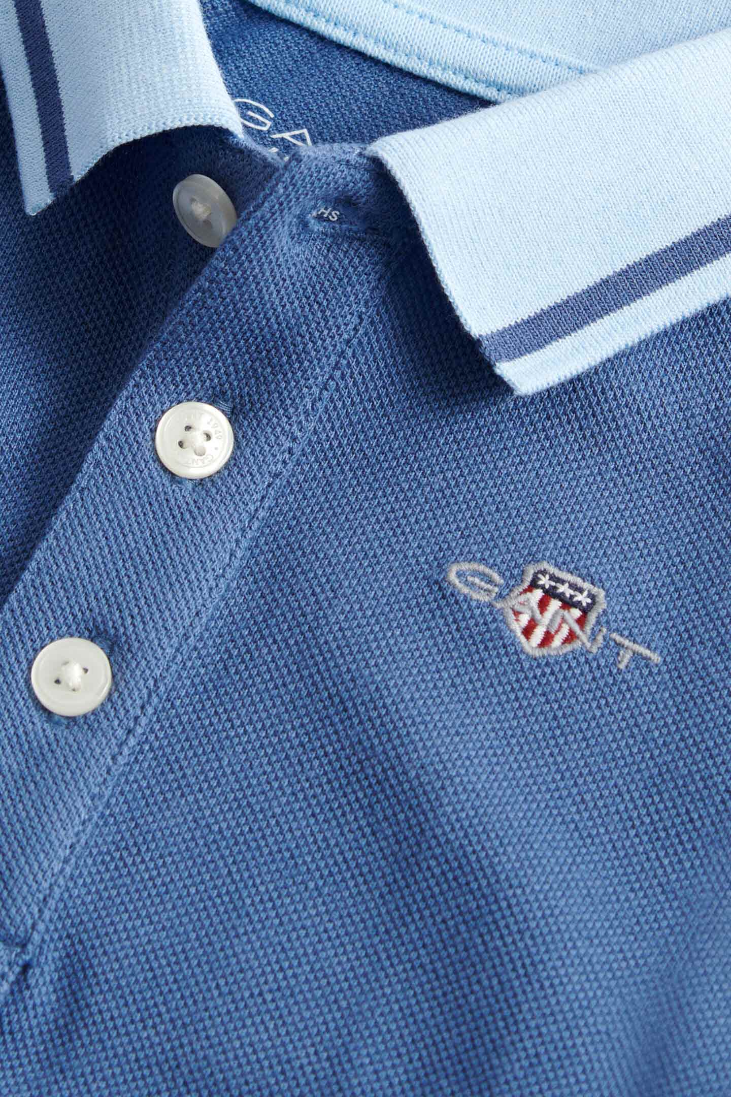 Close-up of a Gant blue cotton pique jumpsuit with button placket and embroidered logo.