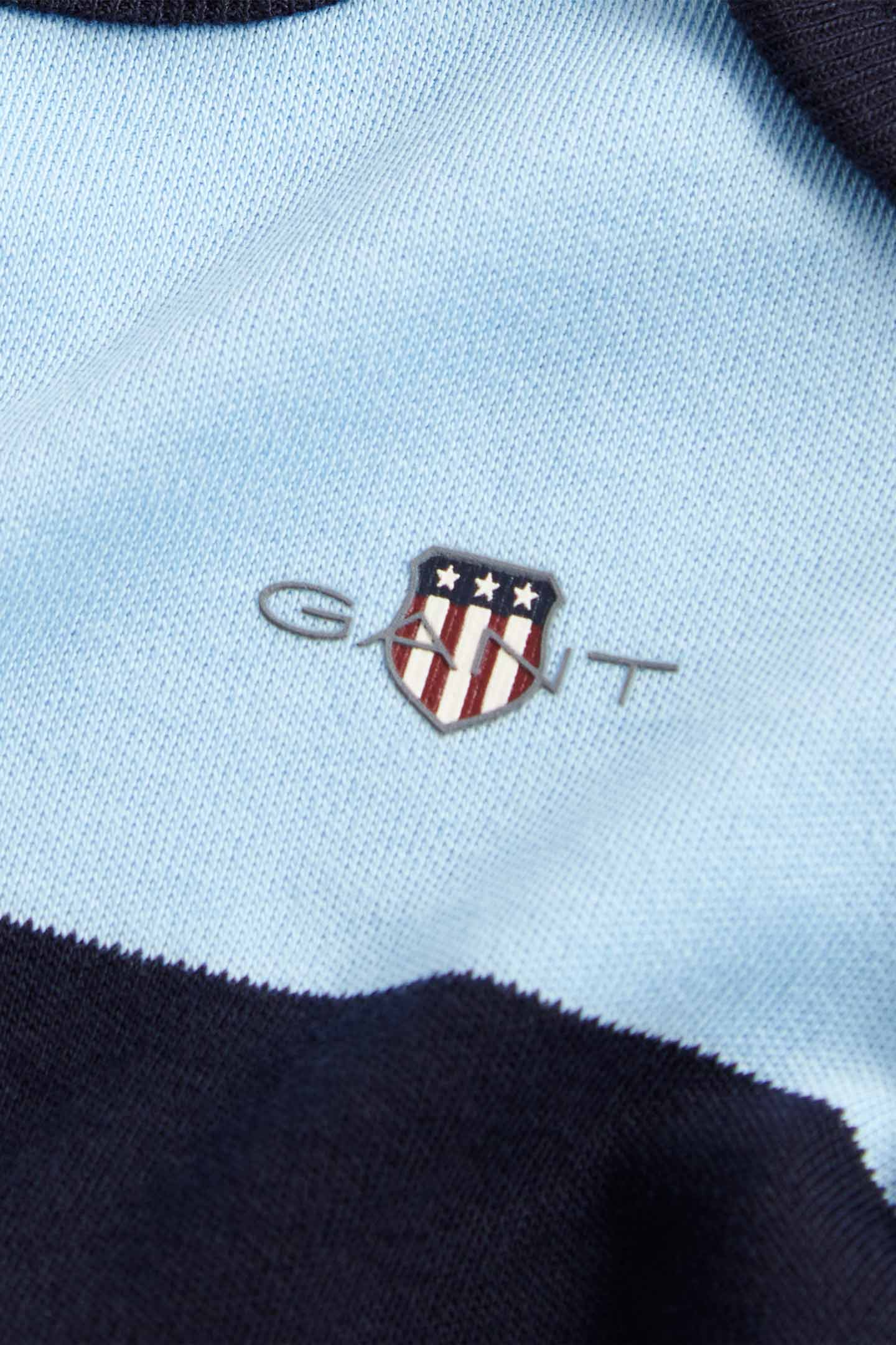 Close-up detail of a GANT baby blue striped romper, highlighting fabric texture and branding.