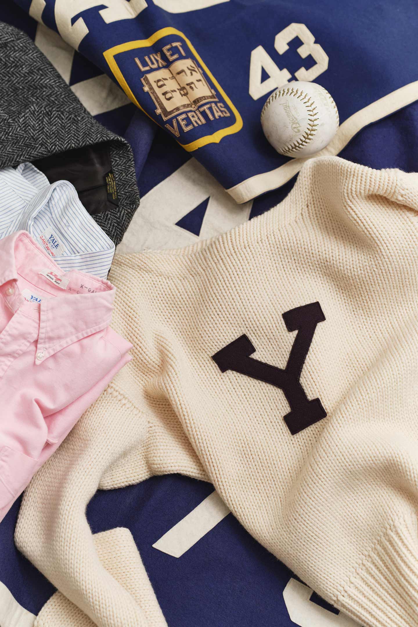 Maglione e camicie collegio vintage Gant disposti con cimeli.