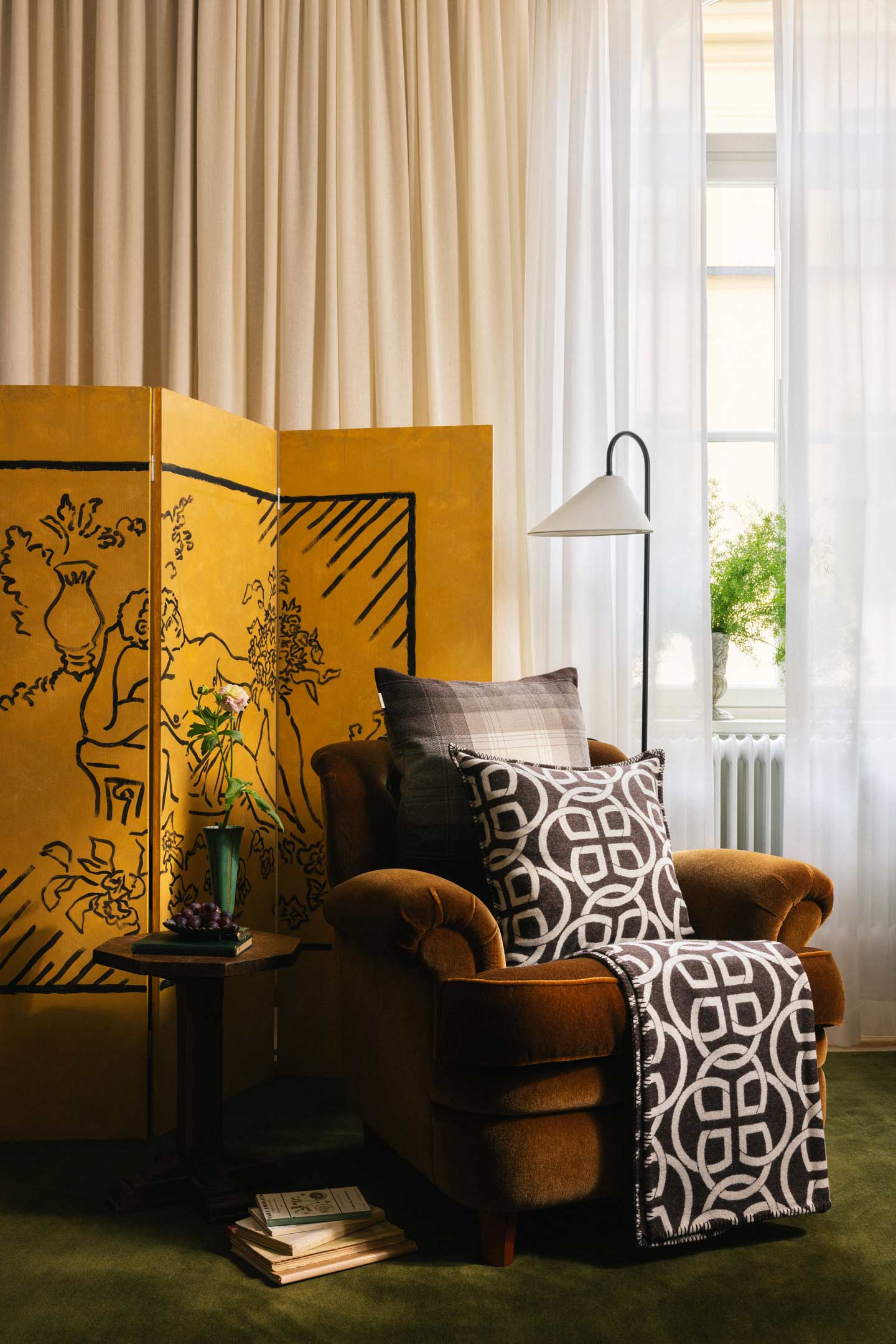 Gant patterned throw and cushion displayed on an armchair beside a decorative room divider.