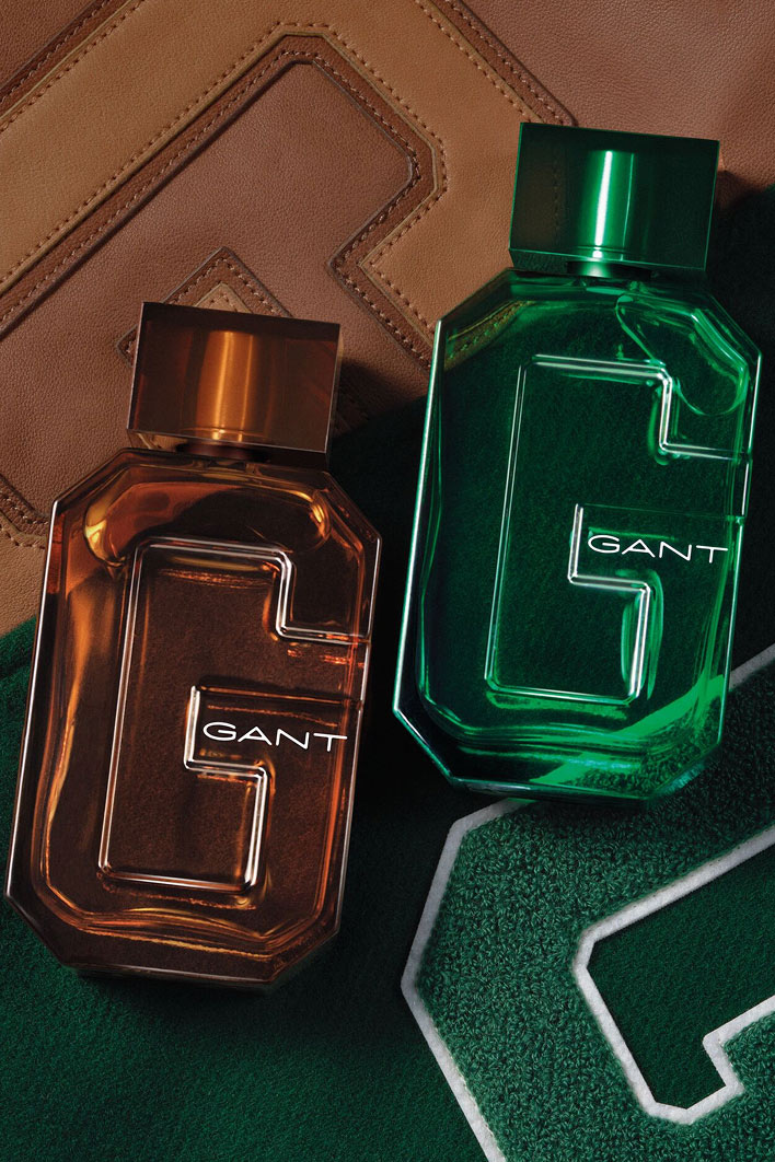 Flacons de parfum GANT ambré et vert avec 'G' embossé, exposés sur tissu cousu